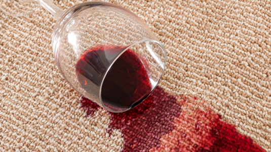 Photo of wine spilling from wine glass staining carpet